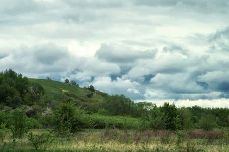Fluffy clouds over beauty spring hills and green valley. True wild nature landscape.の写真素材
