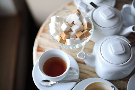 morning Cup of tea stands on the edge of the wooden Desk, square pieces of sugar in the sugar bowl, tea kettle, coffee kettleの写真素材