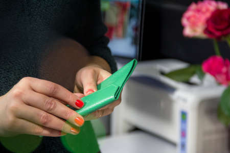 Beautiful girl's hand holds a green female purse, and a bouquet of roses stands nearbyのeditorial素材