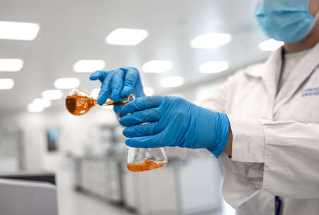 Flasks with brown liquid in scientist hands with dropping chemical liquid to test tubes, science and...