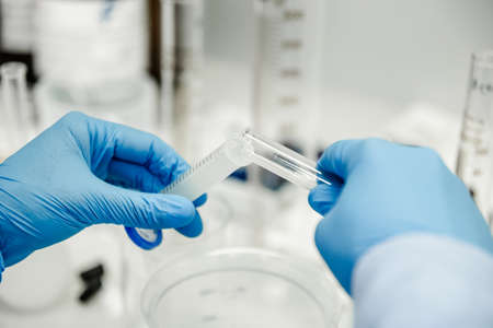 Flask and pipette in scientist hand with dropping chemical liquid to test tubes, science and medical...