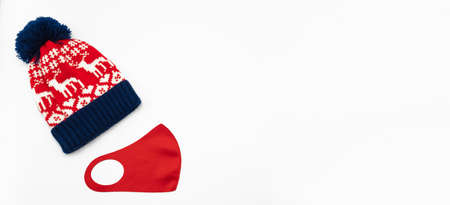 Blue-red winter bobble hat, ski or knit hat with deer and red anti virus protection mask isolated on a white background. New Year and Christmas concept. COVID-19の写真素材