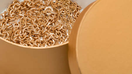 Bijouterie. Gold chains in a beautiful golden box on a white background. Jewelry concept