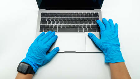 Hands in blue protective gloves lie on the laptop, close up view. Concept of network communications, online shopping or laboratory workの写真素材
