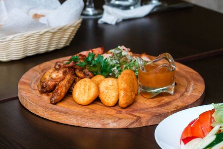 Plate with appetizers of chicken, nuggets and meat rolls with sauce on a wooden plateの写真素材