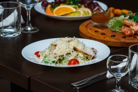 Caesar salad in a white plate on a table in a restaurantの写真素材