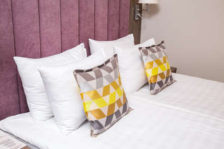 Lilac bed with beautiful linens and pillows, bedside tables and reading lampsの写真素材