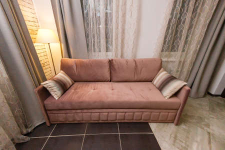 Brown soft sofa in the room with curtains and curtains.の写真素材