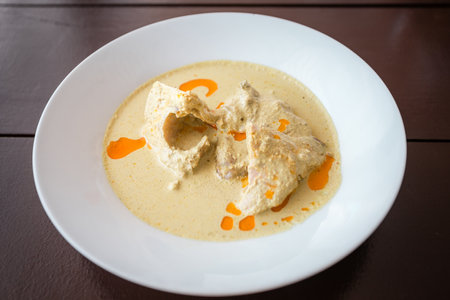 Abkhaz delicious chicken and spice dish with sauce in a white plate on a wooden tableの写真素材