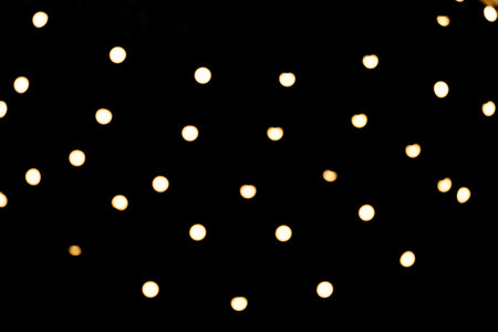 Scattered golden christmas lights bokeh on black backgroundの写真素材