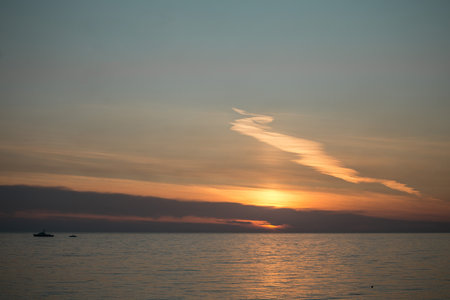 Sunset at sea with the sun hiding behind the cloudsの写真素材