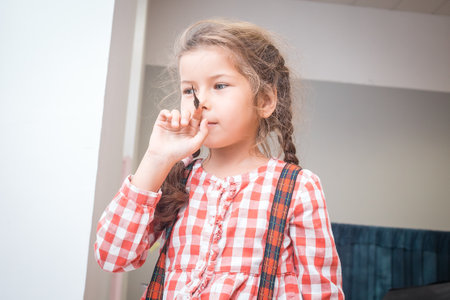 Girl in a plaid shirt trying to plant a butterfly on her nose.の写真素材