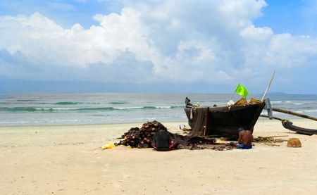 GOA, INDIA - SEPTEMBER 18, 2011:Two fisherman repairfishing net near traditional indian boat on Goa beach, SEPTEMBER 18, 2011のeditorial素材