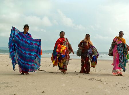 GOA, INDIA - SEPTEMBER 18, 2011: Indian women in traditional dress propose brights  shawll to tourists on the Goa beach, SEPTEMBER 18, 2011のeditorial素材