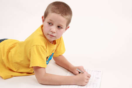 Young boy is writting in his exercise book with pen
