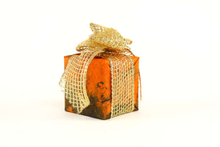 Small christmas present in orange paper with golden tieの写真素材