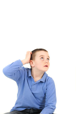 Young boy looking up and scratching head, studio shotの写真素材