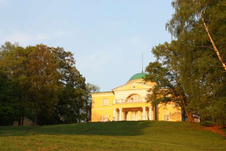 Manor house in the classical style on a hilltop surrounded by park. In the rays of setting sunの写真素材