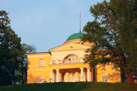Manor house in the classical style on a hilltop surrounded by park. In the rays of setting sunの写真素材