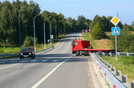 Red tow truck traveling on the road. Traffic signsの写真素材