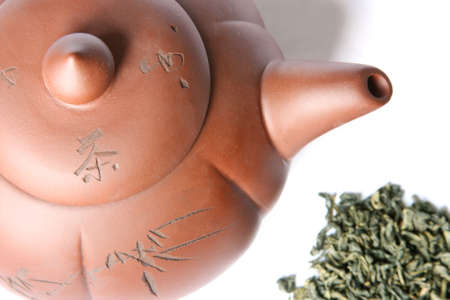 Teapot and a pile of green tea. Isolated on whiteの写真素材