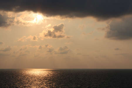 Sun shines through the clouds over seaの写真素材