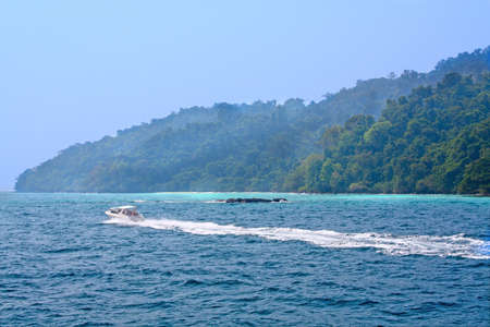 Speedboat pass a tropical island in sunny dayの写真素材