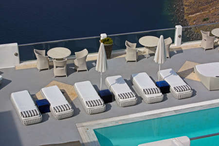 Row of pool chairs and umbrellas. Luxury hotel with caldera view at Santorini, Greece