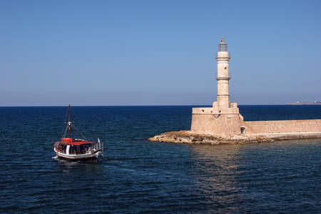 Lighthouse in Chania, Crete, Greece and a boat leaving the harbourの写真素材