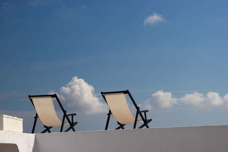 Two deck chairs on a roof against the blue sky  Sunny day の写真素材