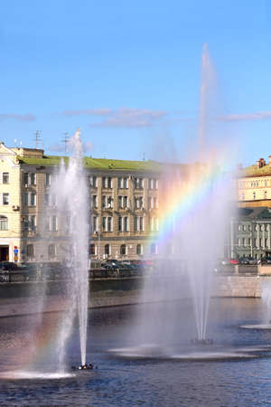 Rainbow Arches Over A Water Fountain in a cityの写真素材