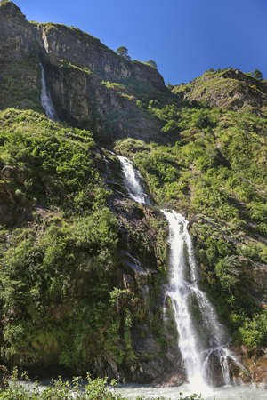 A peaceful waterfall in the mountains of Nepal. Sunflowers on the foregroundの写真素材
