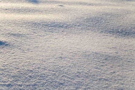 Background of white snow sparkling in the sun. Shallow depth of field