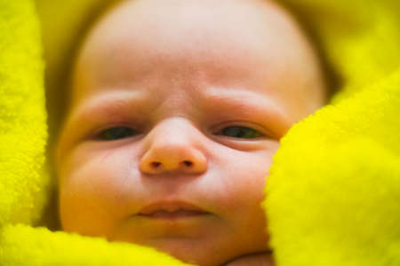 dissatisfied with the baby after a bath in a yellow towelの写真素材