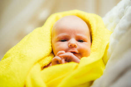dissatisfied with the baby after a bath in a yellow towelの写真素材
