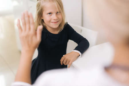 Pediatrician finishes the reception amicably, giving five gesture hand. Young woman doctor...