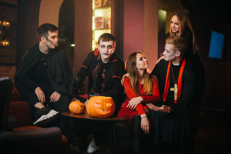 Guy in Count Draculas Halloween costume is sitting with friends in a cafe and looking at the cameraの写真素材