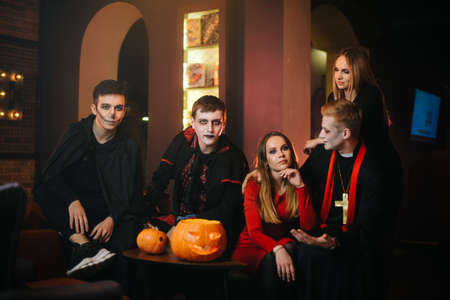 Portrait of friends in Halloween costumes sitting in a cafe and looking at the cameraの写真素材