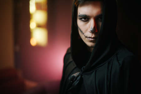 Close-up of a beautiful mans face with Halloween make-up. Young man in Halloween costume looking at the cameraの写真素材