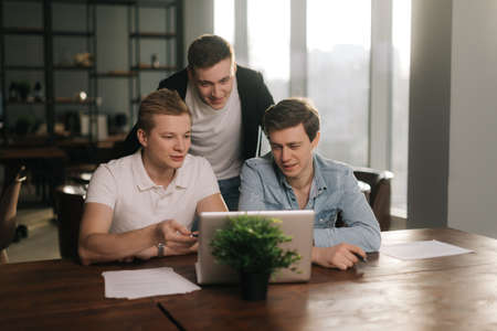 Three male colleagues employees talk work together share ideas on digital marketing strategy at the...