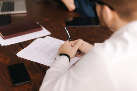 Close-up of working process at business meeting. Young man sits at the table with his laptop.Concept of office life.の写真素材