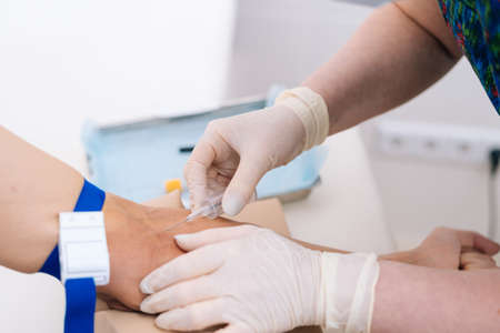 Close-up of hand of man giving blood for biochemical blood testing. Phlebotomist technician drawing blood for testing Coronavirus COVID-19 disease infestation. Concept of healthcare and medicine.の写真素材
