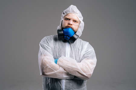 Serious epidemiologist medical worker in protective coveralls, glasses and respirator. Concept of...