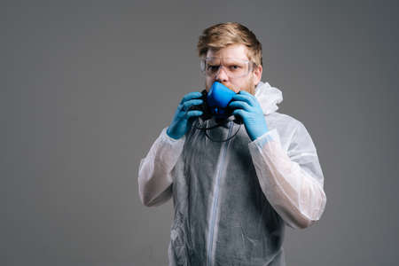 Serious epidemiologist medical worker wearing protective coveralls, goggles and medical respirator looking at the camera. Concept of Coronavirus COVID-19 Pandemic. Studio shot on grey background.の写真素材