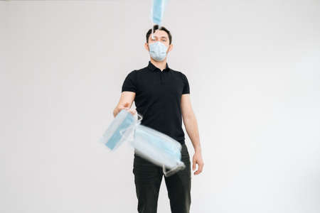Young excited man wearing protective mask throwing medical masks as if they were money bills, on isolated white background. Prevention of virus infection.の写真素材