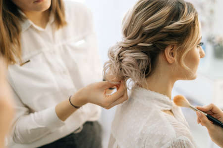 Professional female hairdresser making hairstyle wedding hairstyle for bride in fashion studio. Concept of backstage work.の写真素材