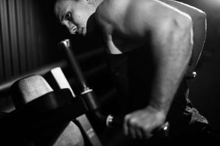 Muscular strong man with perfect beautiful body wearing sportswear doing push-ups on bars during sport workout training in modern gym, black and white color. Concept of healthy lifestyle.の写真素材