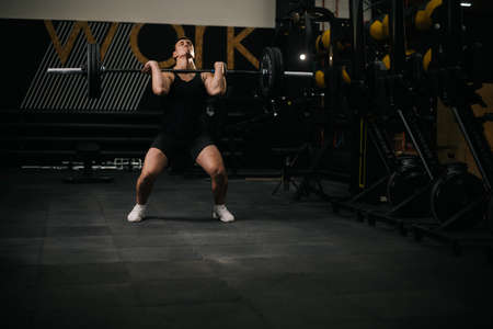 Athletic muscular man with perfect beautiful body wearing sportswear lifting heavy barbell from...