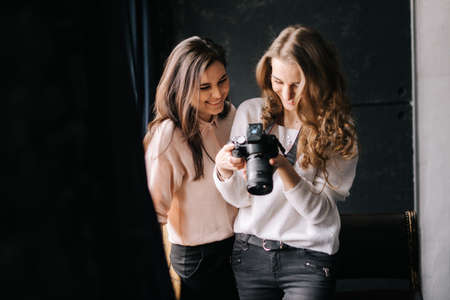 Woman photographer with model looking on camera screen in studio. Concept of creative work in photo studio, backstage job.の写真素材