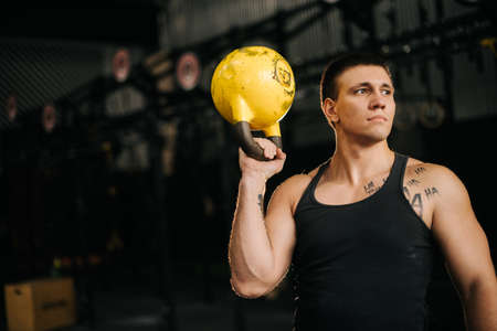 Portrait of Muscular strong man with perfect beautiful body wearing sportswear posing with heavy free weights during sport workout training in modern dark gym. Concept of healthy lifestyle.の写真素材